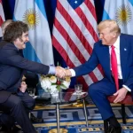 Donald Trump and Javier Milei sitting shaking hands.